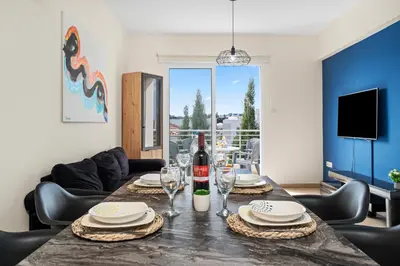 a dining room with a table with wine bottles and glasses at Sunny 2Br Family Apartment - Mythical Sands Resort in Protaras