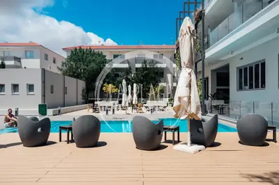 a patio with chairs and an umbrella next to a pool at Sunny 2Br Family Apartment - Mythical Sands Resort in Protaras