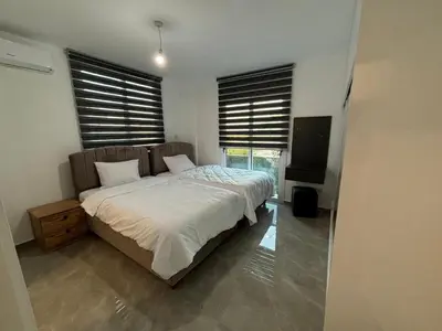 a bedroom with a bed with white sheets and windows at Veray Homes in Nicosia