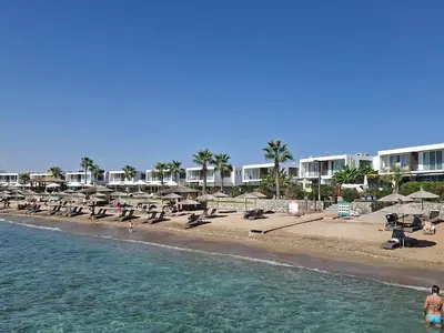 a beach with chairs and umbrellas and the ocean at Chic Blue Apartment with Terrace in Paralimni