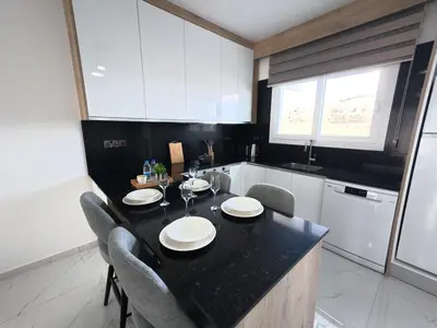 a kitchen with a table with chairs and a black counter top at Chic Sunset Apartment with Terrace in Protaras
