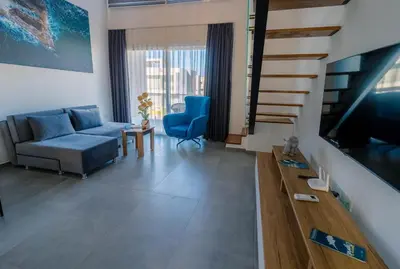 a living room with a couch and a tv at Stylish Loft - 50m from Beach in Paralimni