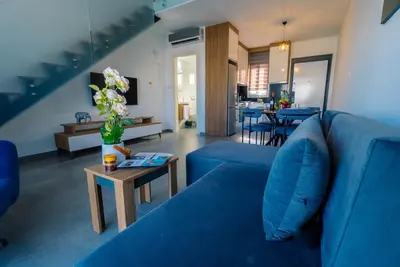 a living room with a blue couch and a table at Stylish Loft - 50m from Beach in Paralimni