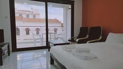 a bedroom with a bed and two chairs and a large window at STAY Terra Cota Studio in Limassol