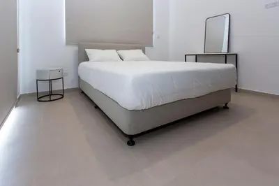 a bedroom with a white bed with two tables and a tv at BlueStar Limassol Suites in Limassol