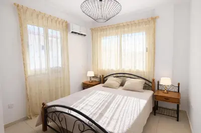 a bedroom with a bed with two night stands and two windows at Villa Dolce Vita II in Protaras