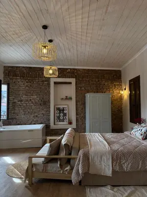 a bedroom with a bed and a brick wall at Aprosmeno Jacuzzi House 7 in Agros