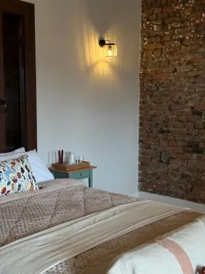 a bedroom with a bed and a brick wall at Aprosmeno Jacuzzi House 7 in Agros