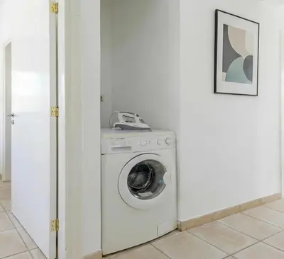 a washing machine in a white room with a phone at Fig Tree Beach Villa Two in Paralimni