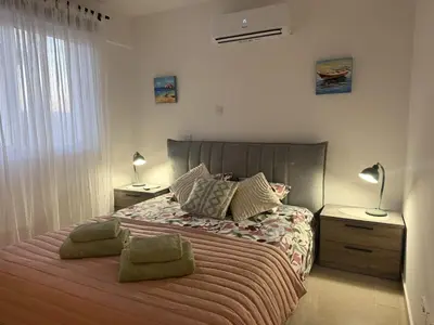 a bedroom with a bed with two lamps and two tables at Thea Court 1 - A in Paralimni