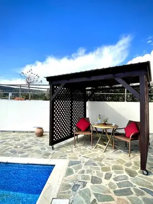 a pavilion with a table and two chairs next to a pool at Stunning villa with breathtaking sea view in Pissouri