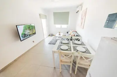 a white dining room with a table and chairs at Amore 1 - A in Paralimni