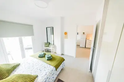 a white bedroom with a bed and a mirror at Amore 1 - A in Paralimni