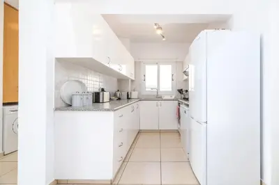 a white kitchen with white cabinets and a refrigerator at Ayia Triada Beach Gardens in Protaras