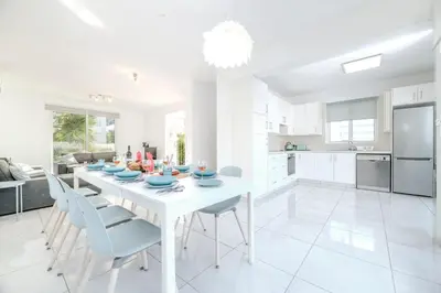a white kitchen and dining room with a white table and chairs at Green Bay Villa #12 in Protaras