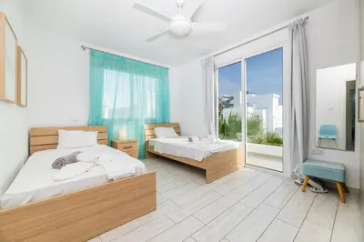 a bedroom with two beds and a large window at Green Bay Villa #12 in Protaras
