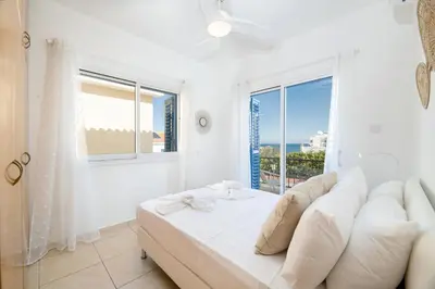 a white room with a bed and a large window at Blue Horizon Villa in Protaras