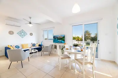a dining room and living room with a table and chairs at Blue Horizon Villa in Protaras