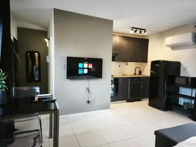 a kitchen with black cabinets and a tv on the wall at 103 St Lazaros View Studio in Larnaka