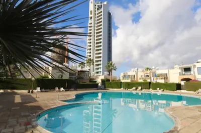 a large swimming pool with a tall building in the background at Cozy flat by the sea with big pool tourist area in Limassol