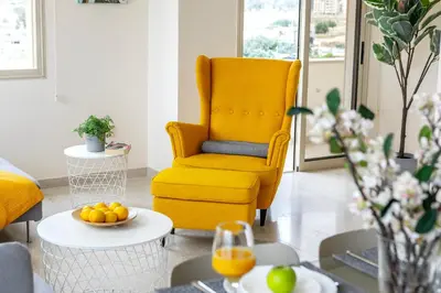 a yellow chair in a living room with oranges on a table at Mackenzie Beachfront Eftyhia Suite in Larnaka