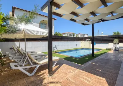 a patio with chairs and an umbrella next to a swimming pool at Villa Anais - 3-Bed Villa with Private Pool in Paralimni