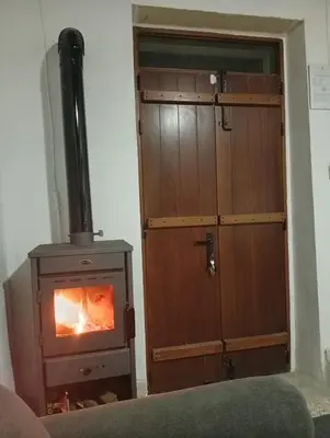 a wood burning stove in a room with a door at En chirokitia cottages in Chirokitia