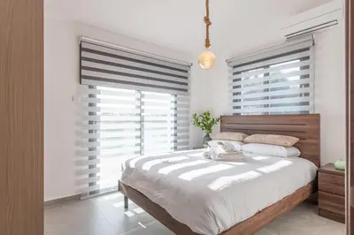a bedroom with a large bed and two windows at TelMar White House - 100m from the Sea in Voroklini