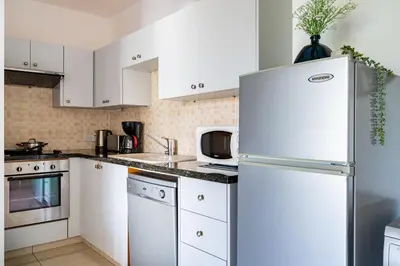 a kitchen with white cabinets and a refrigerator at Odin 1-BR Apartment & Balcony in Larnaca in Larnaka
