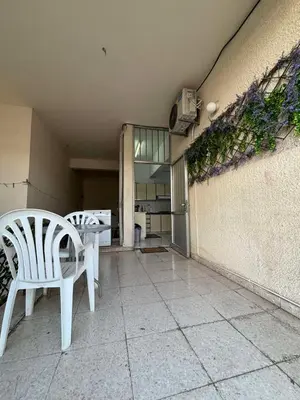 two white chairs sitting on a patio next to a wall at Coast & City Apartment in Limassol