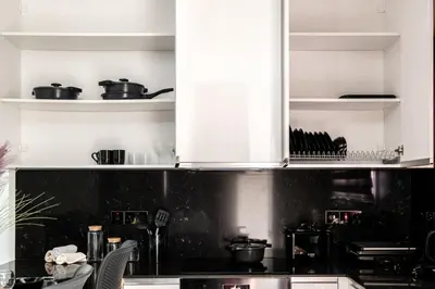 a kitchen with white cabinets and a black counter top at Cozy 1BR Apartment with Terrace in Phrenaros