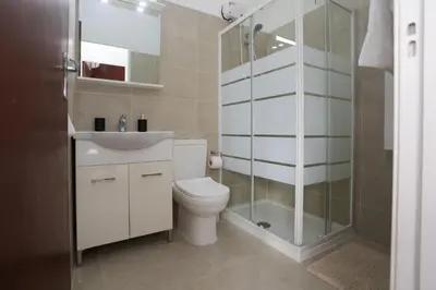 a bathroom with a toilet and a glass shower at Palmove Makenzy Charming 1Bed Apt in Larnaka