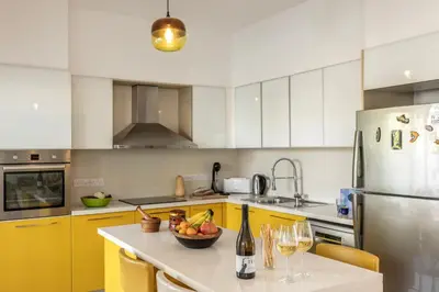 a kitchen with yellow cabinets and a table with a bowl of fruit at Protaras Seaside Villa Narcissos 2 in Protaras