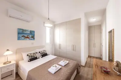 a white bedroom with a bed and a table at Protaras Seaside Villa Narcissos 2 in Protaras