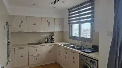 a kitchen with white cabinets and a sink and a window at Sea View Apartment Finikoudes in Larnaka