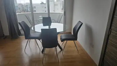 a glass table and chairs in a room with a window at Sea View Apartment Finikoudes in Larnaka