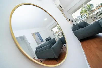 a mirror reflecting a room with couches and chairs at 1 bedroom flat in Nicosia