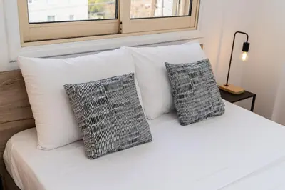 a white bed with three pillows on it at 1 bedroom flat in Nicosia