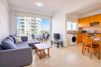 a living room with a couch and a table at Sunset Poolside Apartment with Pool facility in Larnaka