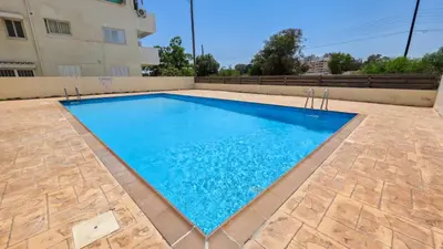 a swimming pool with blue water in front of a building at Sunset Poolside Apartment with Pool facility in Larnaka
