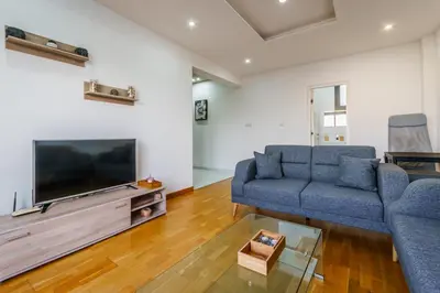 a living room with a blue couch and a flat screen tv at Fam Glam Comfort Apartment in Larnaka