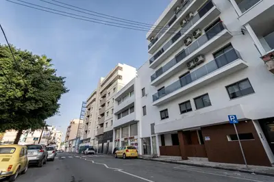 a street with cars parked in front of a building at Fam Glam Comfort Apartment in Larnaka