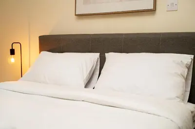 a bed with white sheets and pillows in a room at 1 bedroom flat near center in Nicosia