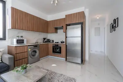 a kitchen with a stainless steel refrigerator and wooden cabinets at Taupe's 2-BR Apartment & Balcony in Larnaca in Livadhia
