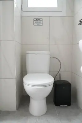 a white toilet in a bathroom with a window at Athalassas corner in Strovolos