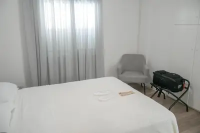 a room with a bed and a chair and a suitcase at Athalassas corner in Strovolos