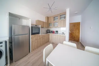 a kitchen with a stainless steel refrigerator and wooden cabinets at Armonia Seafront Studio in Limassol