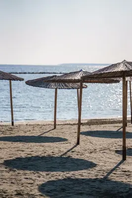 a group of straw umbrellas on a beach at Armonia Seafront Studio in Limassol