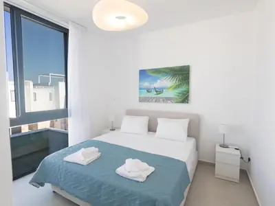 a white bedroom with a bed and a large window at Holiday Home Protaras Aqua Pearl Villa AQ16 by Interhome in Protaras