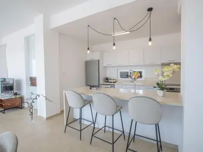 a kitchen with white cabinets and a island with stools at Holiday Home 3-Schlafzimmer-Villa mit privatem Pool im Zentrum by Interhome in Protaras